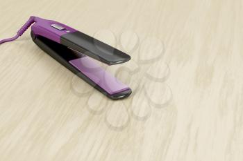 Ceramic hair straightener on wooden table  