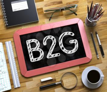 Small Chalkboard with B2G Concept. Business Concept - B2G Handwritten on Red Small Chalkboard. Top View Composition with Chalkboard and Office Supplies on Office Desk. 3d Rendering.