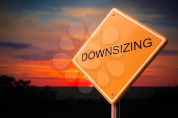 Downsizing on Warning Road Sign on Sunset Sky Background.