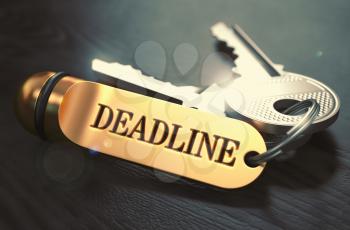 Keys and Golden Keyring with the Word Deadline over Black Wooden Table with Blur Effect. Toned Image.