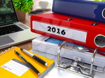 Red Ring Binder with Inscription 2016 on Background of Working Table with Office Supplies, Laptop, Reports. Toned Illustration. Business Concept on Blurred Background.