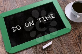 Handwritten Do on Time on a Green Chalkboard. Top View Composition with Chalkboard and White Cup of Coffee.