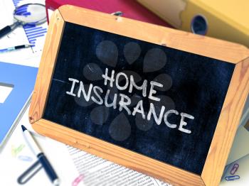 Home Insurance Handwritten on Chalkboard. Composition with Small Chalkboard on Background of Working Table with Ring Binders, Office Supplies, Reports. Blurred Background. Toned Image.