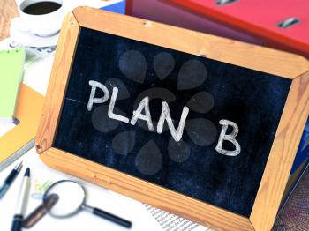 Plan B Handwritten on Chalkboard. Composition with Small Chalkboard on Background of Working Table with Ring Binders, Office Supplies, Reports. Blurred Background. Toned Image.