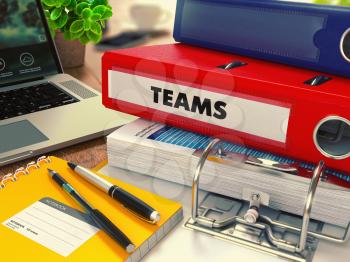 Red Office Folder with Inscription Teams on Office Desktop with Office Supplies and Modern Laptop. Business Concept on Blurred Background. Toned Image.