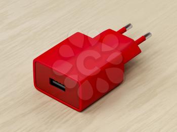 Red smartphone charger with USB port on wooden desk