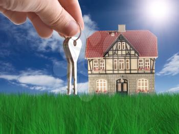 Royalty Free Clipart Image of a Person Holding Keys By a House