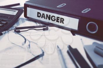 Danger - Office Folder on Background of Working Table with Stationery, Glasses, Reports. Business Concept on Blurred Background. Toned Image.