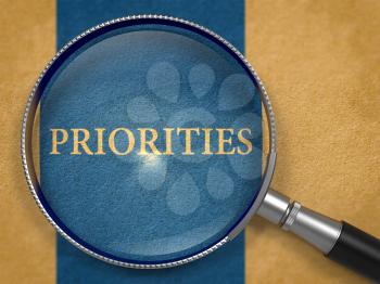 Priorities Concept through Magnifier on Old Paper with Dark Blue Vertical Line Background. 3D Render.
