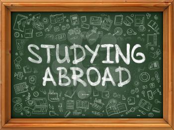 Studying Abroad - Hand Drawn on Chalkboard. Studying Abroad with Doodle Icons Around.