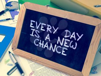 Every Day is a New Chance Handwritten on Chalkboard. Composition with Small Chalkboard on Background of Working Table with Ring Binders, Office Supplies, Reports. Blurred, Toned Image. 3D Render.
