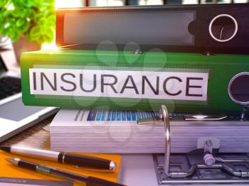Insurance - Green Office Folder on Background of Working Table with Stationery and Laptop. Insurance Business Concept on Blurred Background. Insurance Toned Image. 3D.
