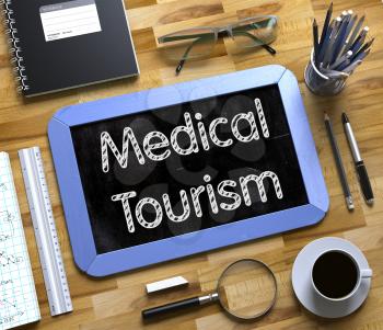Medical Tourism Handwritten on Blue Small Chalkboard. Top View of Wooden Office Desk with a Lot of Business and Office Supplies on It. Small Chalkboard with Medical Tourism Concept. 3d Rendering.