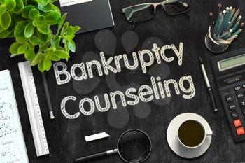 Black Chalkboard with Handwritten Business Concept - Bankruptcy Counseling - on Black Office Desk and Other Office Supplies Around. Top View. 3d Rendering. Toned Illustration.