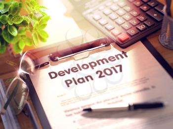 Development Plan 2017 on Clipboard with Sheet of Paper on Wooden Office Table with Business and Office Supplies Around. 3d Rendering. Blurred Illustration.