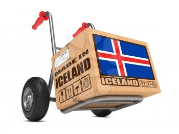 Cardboard Box with Flag of Iceland and Made in Iceland Slogan on Hand Truck White Background. Free Shipping Concept.