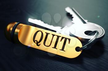 Keys and Golden Keyring with the Word Quit over Black Wooden Table with Blur Effect. Toned Image.