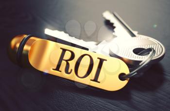Keys and Golden Keyring with the Word ROI - Return On Investment - over Black Wooden Table with Blur Effect. Toned Image.