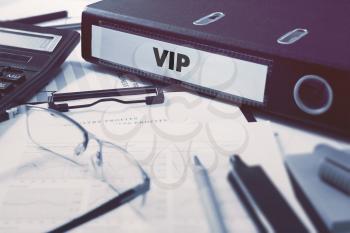 Ring Binder with inscription VIP - Very Important Person - on Background of Working Table with Office Supplies, Glasses, Reports. Toned Illustration. Business Concept on Blurred Background.