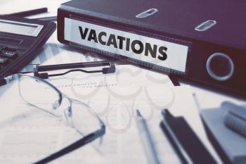 Vacations - Office Folder on Background of Working Table with Stationery, Glasses, Reports. Business Concept on Blurred Background. Toned Image.
