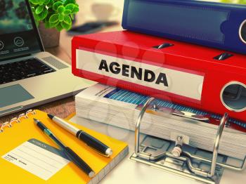 Red Office Folder with Inscription Agenda on Office Desktop with Office Supplies and Modern Laptop. Business Concept on Blurred Background. Toned Image.