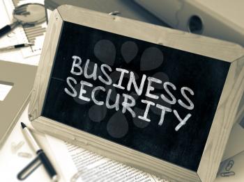 Business Security Handwritten by White Chalk on a Blackboard. Composition with Small Chalkboard on Background of Working Table with Office Folders, Stationery, Reports. Blurred, Toned Image.