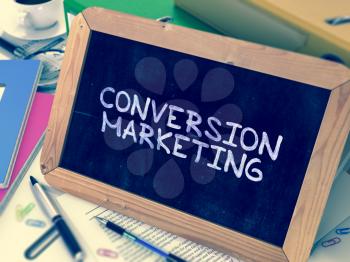 Conversion Marketing Handwritten by White Chalk on a Blackboard. Composition with Small Chalkboard on Background of Working Table with Office Folders, Stationery, Reports. Blurred, Toned Image.