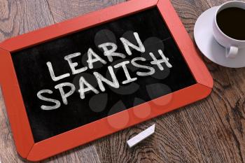 Learn Spanish Concept Hand Drawn on Red Chalkboard on Wooden Table. Business Background. Top View.