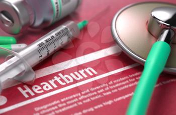 Heartburn - Printed Diagnosis with Blurred Text on Red Background and Medical Composition - Stethoscope, Pills and Syringe. Medical Concept.