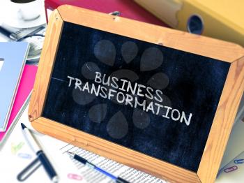 Business Transformation - Chalkboard with Hand Drawn Text, Stack of Office Folders, Stationery, Reports on Blurred Background. Toned Image.