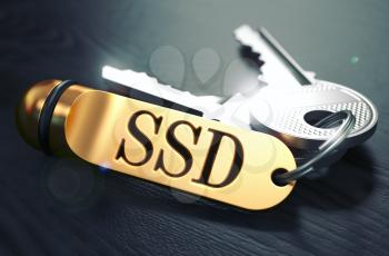 Keys and Golden Keyring with the Word SSD - Solid State Disk - over Black Wooden Table with Blur Effect. Toned Image.