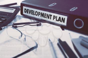 Development Plan - Office Folder on Background of Working Table with Stationery, Glasses, Reports. Business Concept on Blurred Background. Toned Image.