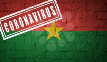 Flag of the Burkina Faso on brick wall texture. stamped of Coronavirus. Corona virus concept. On the verge of a COVID-19 or 2019-nCoV Pandemic. Novel Chinese Coronavirus outbreak