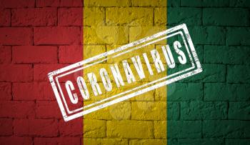 Flag of the Guinea on brick wall texture. stamped of Coronavirus. Corona virus concept. On the verge of a COVID-19 or 2019-nCoV Pandemic. Novel Chinese Coronavirus outbreak