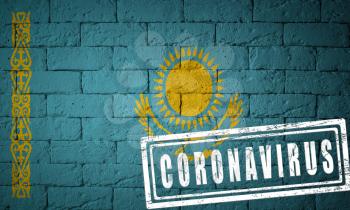 Flag of the Kazakhstan with original proportions. stamped of Coronavirus. brick wall texture. Corona virus concept. On the verge of a COVID-19 or 2019-nCoV Pandemic.