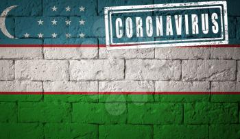 Flag of the Uzbekistan with original proportions. stamped of Coronavirus. brick wall texture. Corona virus concept. On the verge of a COVID-19 or 2019-nCoV Pandemic.
