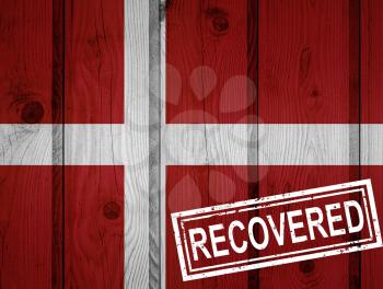 flag of Denmark that survived or recovered from the infections of corona virus epidemic or coronavirus. Grunge flag with stamp Recovered