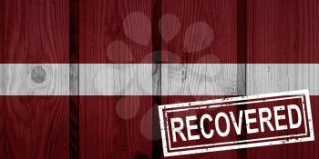 flag of Latvia that survived or recovered from the infections of corona virus epidemic or coronavirus. Grunge flag with stamp Recovered