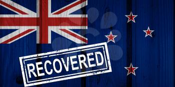 flag of New Zealand that survived or recovered from the infections of corona virus epidemic or coronavirus. Grunge flag with stamp Recovered