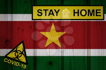 Flag of the Suriname in original proportions. Quarantine and isolation - Stay at home. flag with biohazard symbol and inscription COVID-19.
