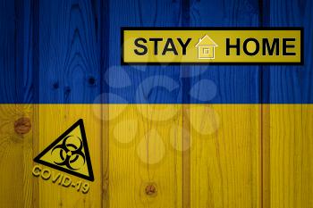 Flag of the Ukraine in original proportions. Quarantine and isolation - Stay at home. flag with biohazard symbol and inscription COVID-19.
