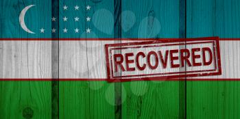 flag of Uzbekistan that survived or recovered from the infections of corona virus epidemic or coronavirus. Grunge flag with stamp Recovered